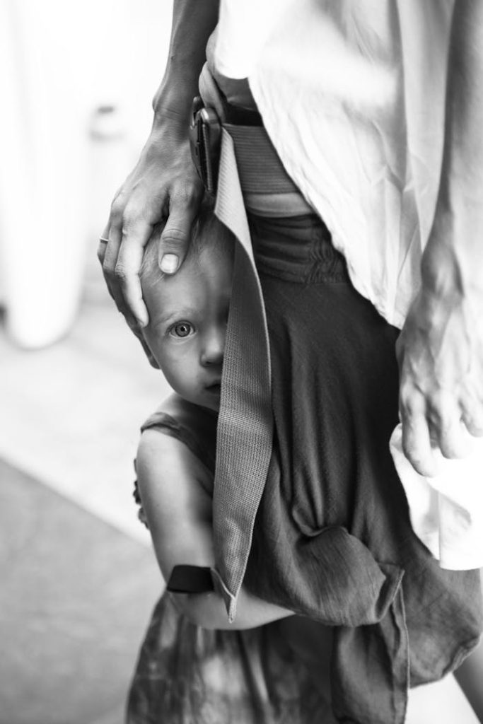 A young child seeks comfort by clinging to an adult's leg, displaying trust and attachment.